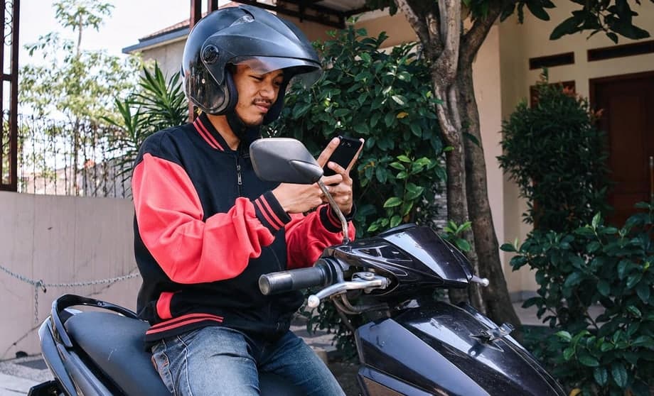 Motociclista conferindo o celular ao lado da moto
